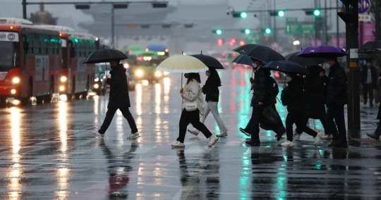 전국이 대체로 흐리고 비가 내리는 13일 오전 서울 종로구 광화문 세종대로 사거리에서 출근길 시민들이 우산을 쓰고 이동하고 있다. [연합뉴스]